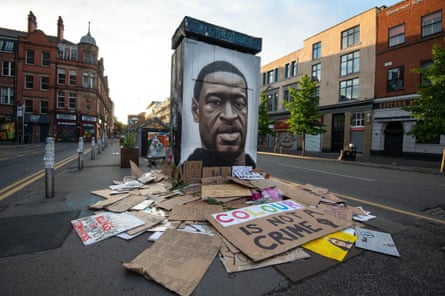 Placards from a BLM demonstration in Manchester are left next to a mural of George Floyd, 6 June 2020.