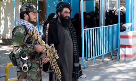 Des combattants talibans montent la garde alors que des étudiantes arrivent pour les examens d'entrée à l'université de Kaboul, octobre 2022.