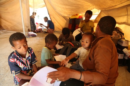 Ahmed Ali Muqbel Ali teaches his children in their tent in Al-Malika camp for displaced people in Taiz, Yemen, after the closure of the schools because of Covid-19.