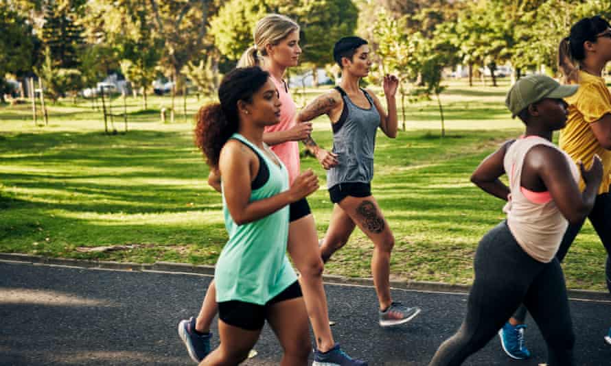 Young women jog or speed-walk through a city park