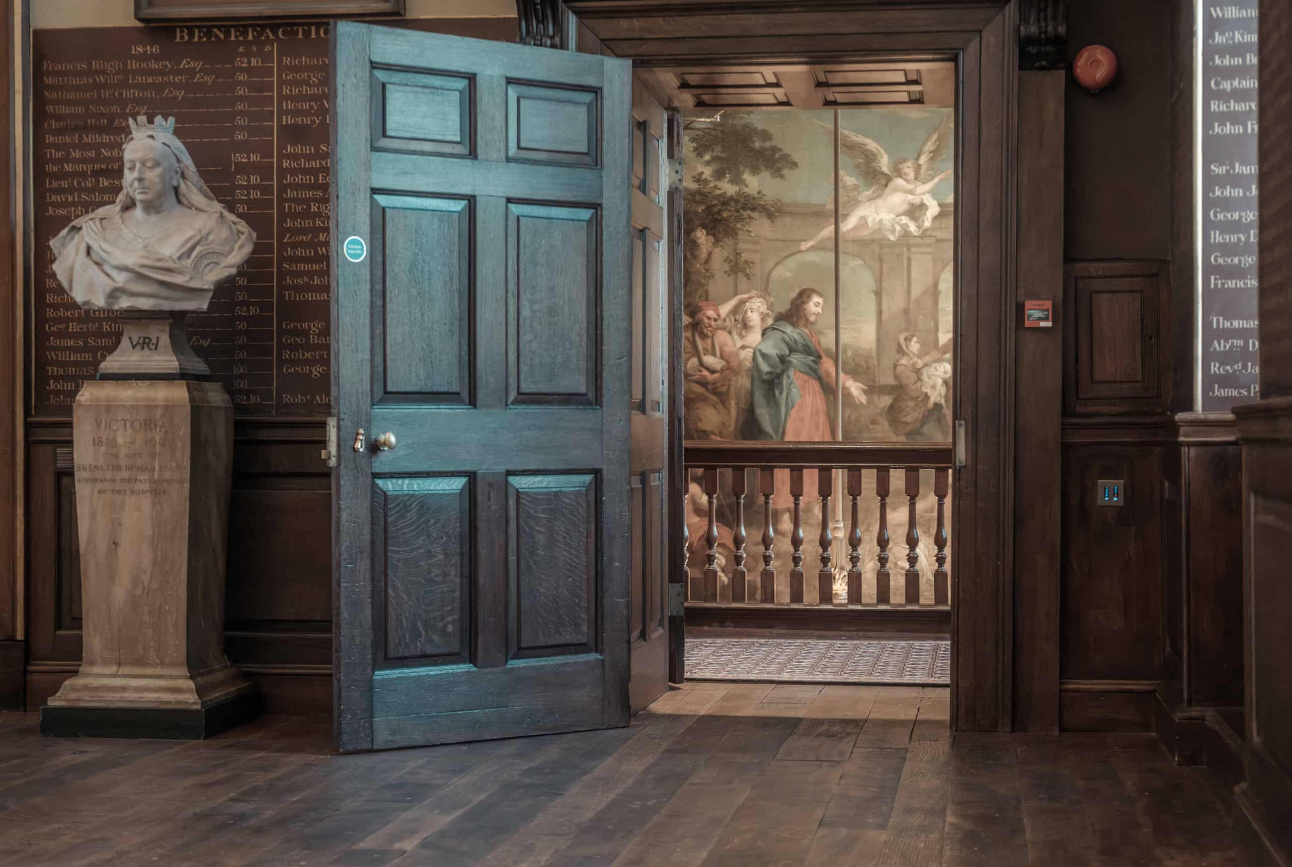 A doorway in the Great Hall, through which an ornate painting covering a wall is visible