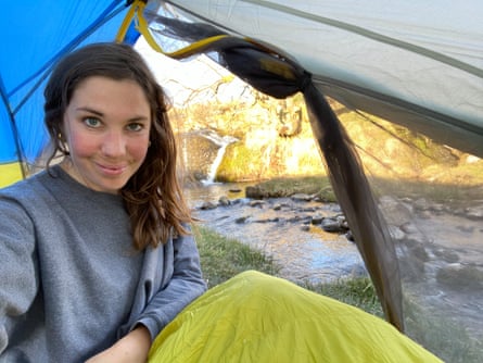 Young woman smiling in a tent with a river behind.