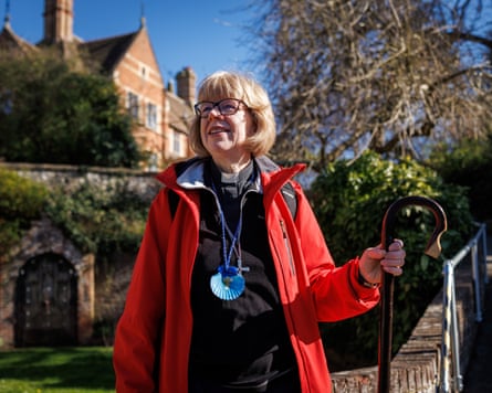 Sarah Mullally in a red coat standing holding a crook