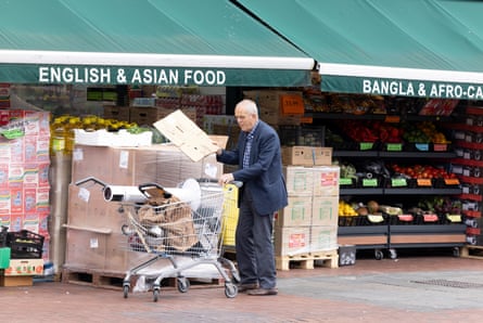 An elderly man pushes a trolley in front of a shop with an awning that reads: 'English and Asian food' on one side and 'Bangla and Afro-Caribbean' on the other.