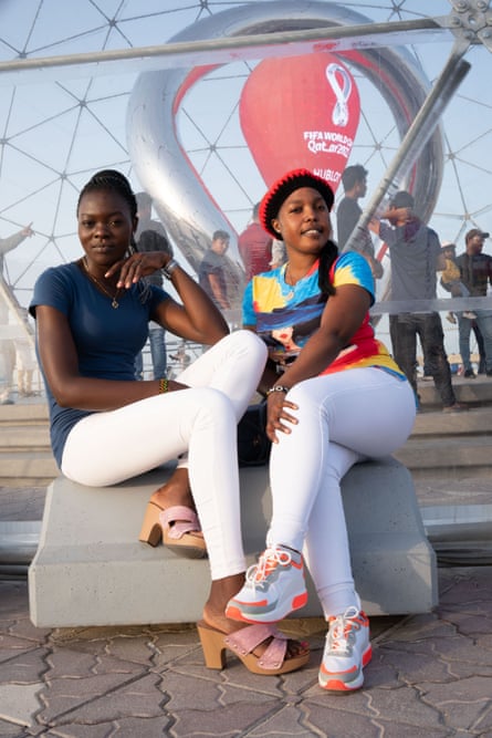 Roomates Teresa and Sherryl, from Kenya, sit on a lounger by the waterfront in Doha, Qatar on a blue-sky day.