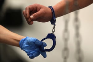 An Ice agent takes handcuffs off before booking an immigrant in Los Angeles, California.