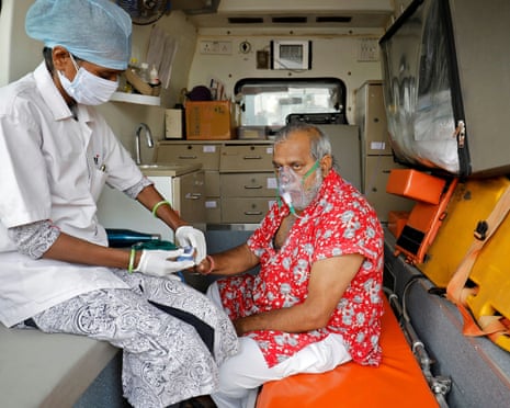 A paramedic uses an oximeter to check the oxygen level of a patient inside an ambulance while waiting to enter a Covid-19 hospital for treatment.