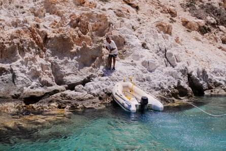 A boat pulling up to a rocky shore
