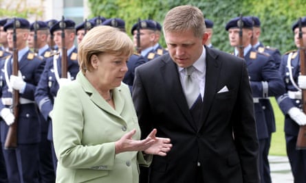 Fico talks to Angela Merkel with a guard of honour in the background
