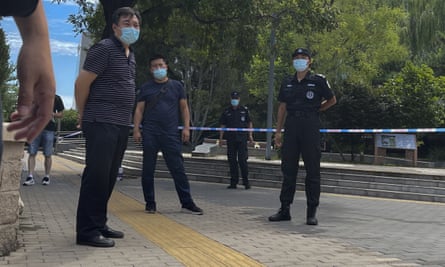 Plainclothes police and security guards wearing face masks stand guard outside the court in Beijing