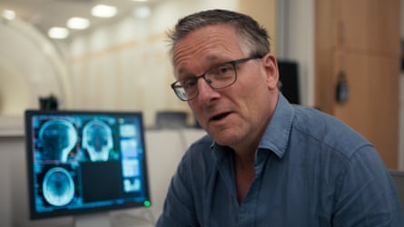 Dr Michael Mosley sitting next to a hospital computer screen.