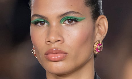 A Versace model wearing green winged eye make-up and pink lipstick