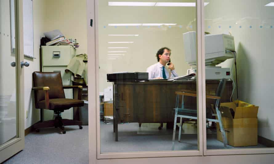 Man sitting at desk, on phone, in front of huge computer