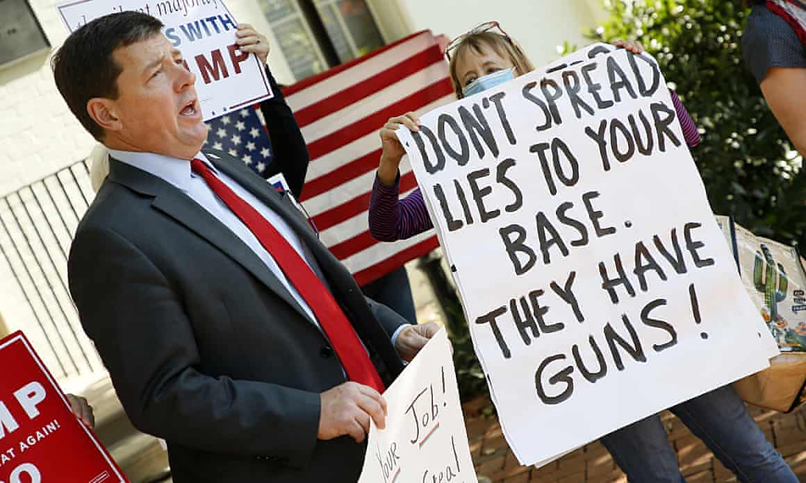 A person holding a sign reading 'Don't spread lies to your based' stands near Ed Martin