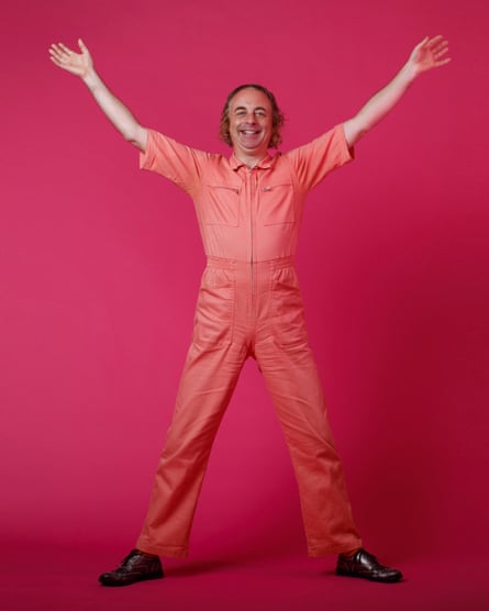Paul Foot, arms aloft, wearing a pink jumpsuit