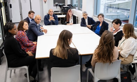 Sadiq Khan and Jess Phillips sit at a desk with staff of Croydon custody centre