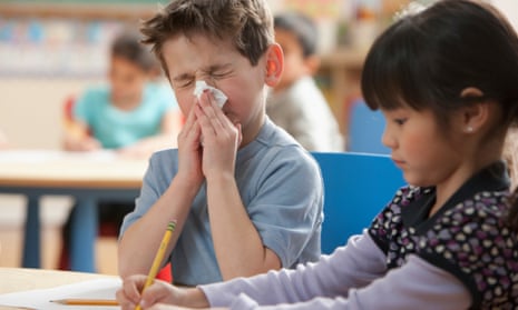Boy blowing his nose in a classroom