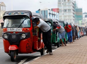Drivers push auto rickshaws in a queue to buy petrol in Colombo amid Sri Lanka’s economic crisis