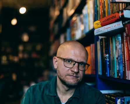 Oleksandr Mykhed besides bookshelves in a bookshop