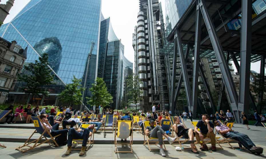People sit on deckchairs near the Lloyds of London building during the heatwave.