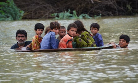 A man uses a satellite dish to move children across a flooded area in Balochistan province, Pakistan.