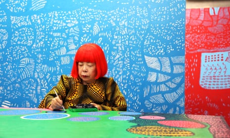 Yayoi Kusama at work in her studio, in front of her painting The Moving Moment When I Went to the Universe.
