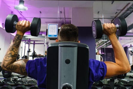 A man lifts weights while sitting down at the gym