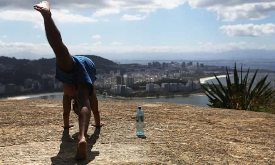 A man performs yoga at the top of the Babilônia favela.