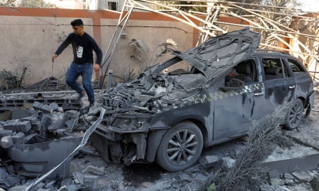A man walks near a destroyed vehicle 