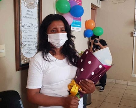 A woman in a surgical mask holding a bouquet of flowers.