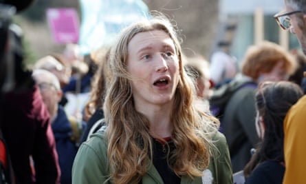 Ellie Gomersall, a young woman with long brown hair in a green jacket, speaking outside.