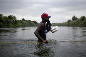A person seeking refuge in the US wades through the Rio Grande from Ciudad Acuna towards Del Rio, carrying supplies
