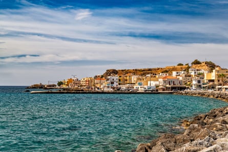A town of whitewashed buildings and terracotta roofs around a turquoise crescent bay