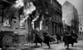 Russian troops charge down a street with buildings ablaze during the advance through Poland, 1944
