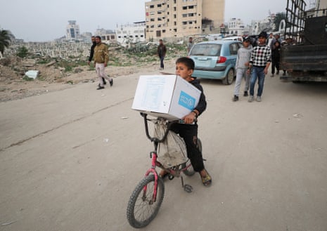 A Palestinian boy carries an aid box provided by Unrwa in Gaza City in February 2025.