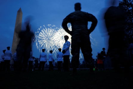 Soldiers and members of a military band watch fireworks explode at the Washington Monument.