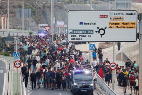 Spanish police officers and soldiers escort a big group of migrants to the border in Ceuta.