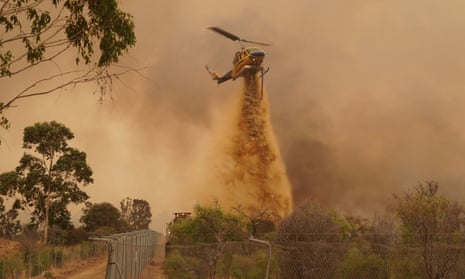 A helicopter drops retardant as WA firefighters work to contain a fire outside Wooroloo