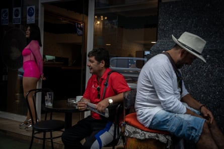 A man shines shoes next to Café Atenas, a café con piernas in Santiago, Chile.
