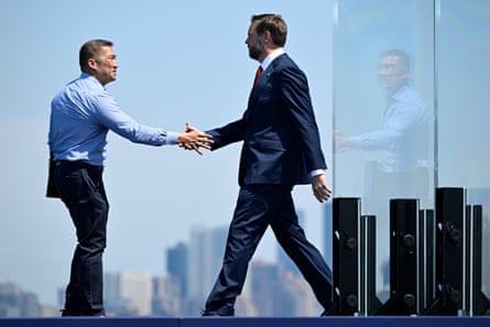 Two men shake hands with a cityscape in the background.