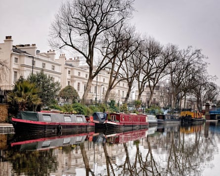 Narrowboats on a London canal in winter with trees reflecting in the water