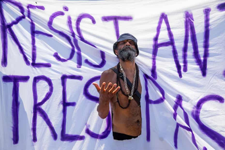 A man emerges through a banner saying 'resist and trespass' at the 'kill the bill' protest