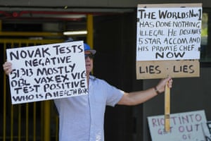A supporter of Serbian Novak Djokovic holds placards outside an immigration detention hotel where Djokovic is confined in Melbourne, Australia, Monday, Jan. 10, 2022.