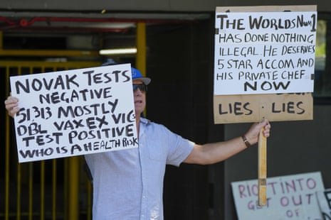 A supporter of Djokovic holds placards outside an immigration detention hotel where the athlete is staying in Melbourne, Australia.