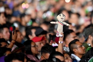 A person in a crowd holds a doll over their head