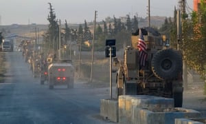 US military vehicles travel down a main road in northeast Syria