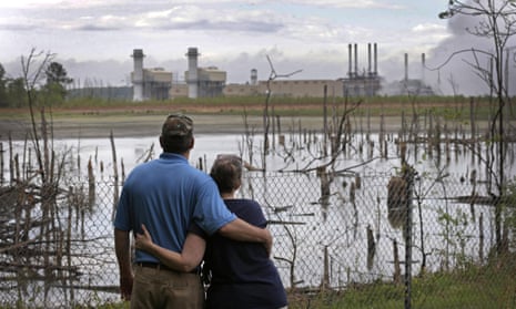 In this 25 April 2014, file photo, Bryant Gobble and his wife, Sherry, look from their yard across an ash pond full of dead trees toward Duke Energy’s Buck Steam Station in Dukeville, North Carolina.
