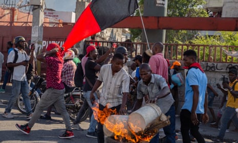 People in front flames with black and red Haiti flag behind them