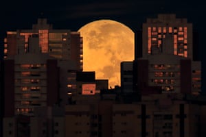 The moon is partially covered by buildings in Brasilia, Brazil, at the start of a total lunar eclipse