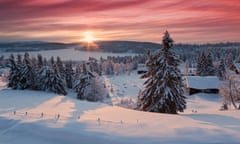 Sunrise on snow covered village in Norway<br>View of snow covered firs and log cabins situated on shore of Lake Lillehammer, Norway.